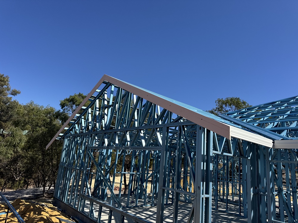 Completed steel roof trusses on a house frame under a blue sky